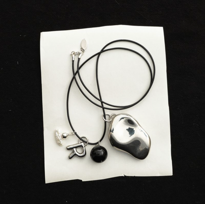 Everyday Talisman Necklace by Space of Time x Sea + Pattern: silver balm case on a beaded leather cord necklace with letter charm