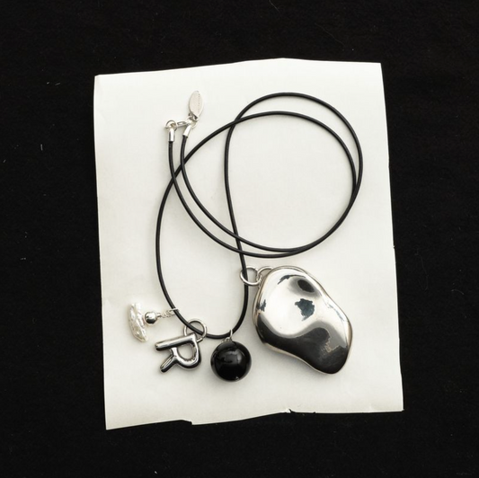 Everyday Talisman Necklace by Space of Time x Sea + Pattern: silver balm case on a beaded leather cord necklace with letter charm