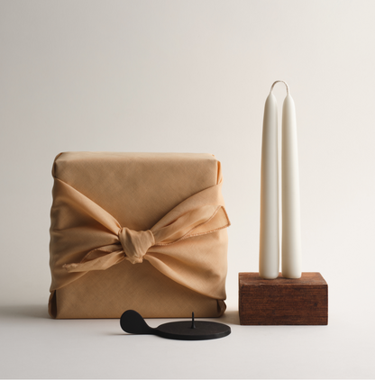 fabric wrapped gift box with pair of off-white taper candles and candle holder